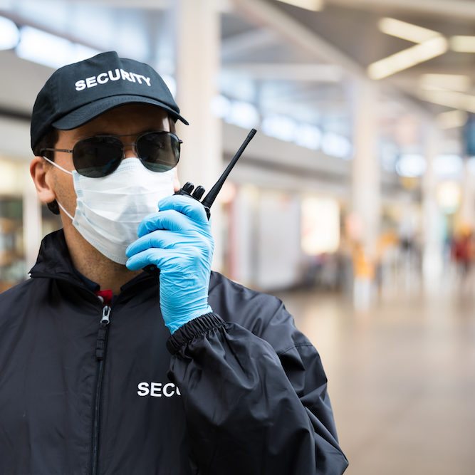 Security Guard Standing In Face Mask In Airport Terminal